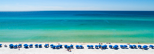 Aerial view of the white sand beaches and emerald green waters of the Gulf of Mexico behind the Watersound Beach Club