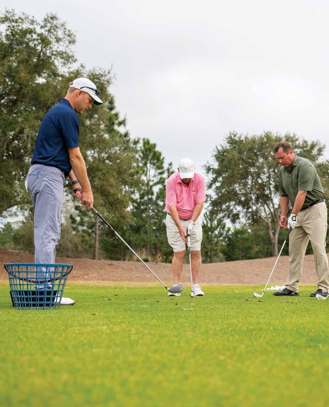 Golf instructor Ben Blalock shows two golfers proper form on the putting green
